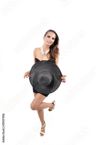 Attractive woman wearing black dress, hat and pearls.
