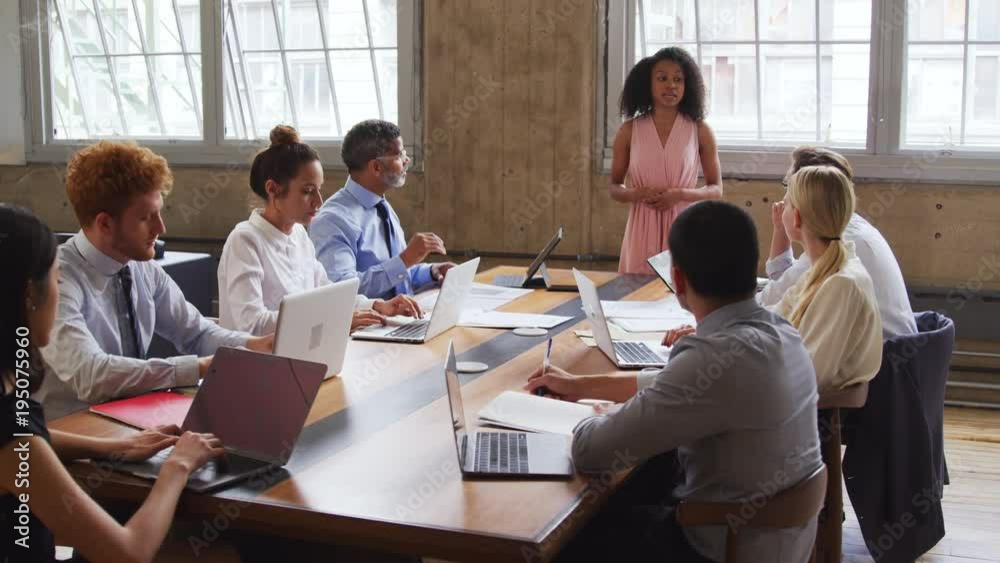 Black female boss stands talking at a boardroom meeting Black female boss stands talking at a boardroom meeting