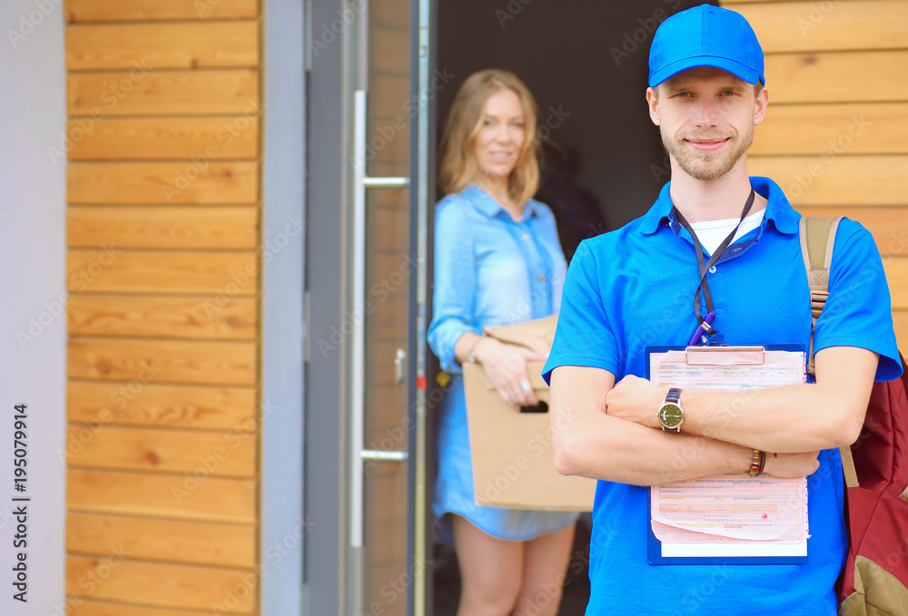 Smiling delivery man in blue uniform delivering parcel box to recipient - courier service concept. Smiling delivery man in blue uniform Smiling delivery man in blue uniform delivering parcel box to recipient - courier service concept. Smiling delivery man in blue uniform