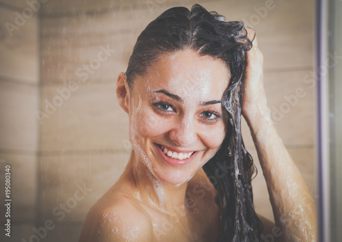 Young beautyful woman under shower in bathroom.