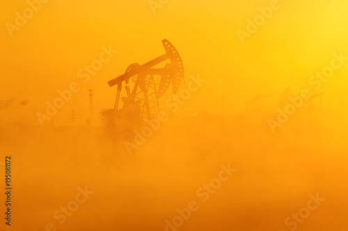 The oil sucking machines in the vapour lakeside sunrise.