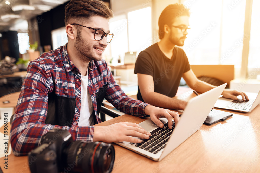 Two freelancer men working at different laptops at desk. Two freelancer men working at different laptops at desk.