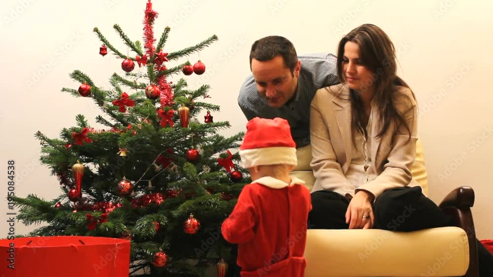 Young parents and little Santa Claus child near Christmas tree Young parents and little Santa Claus child near Christmas tree