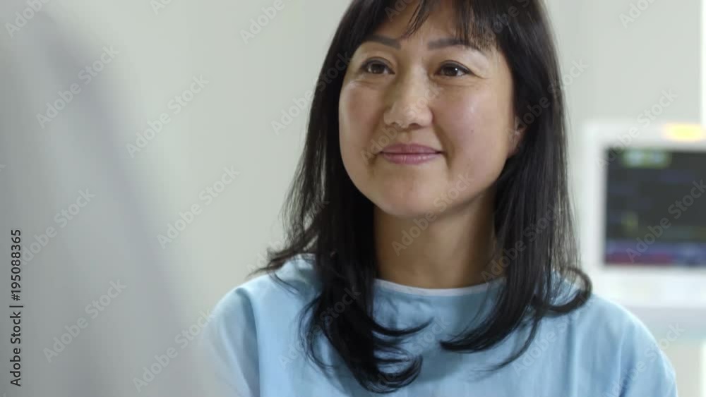 Tilt up of cheerful female patient in hospital gown nodding and listening to her doctor talking about successful treatment Tilt up of cheerful female patient in hospital gown nodding and listening to her doctor talking about successful treatment