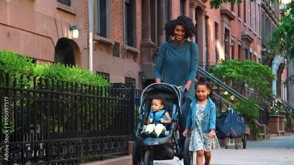 Mother pushing buggy with two daughters in the street