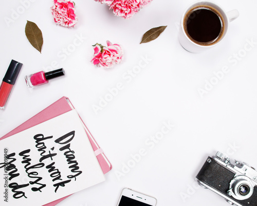 Woman fashion home office desk workspace with handwritten quote notebook, pink carnation flowers, coffee cup, smartphone and cosmetics on white background. Flat lay. Top view. Stylish female concept.
