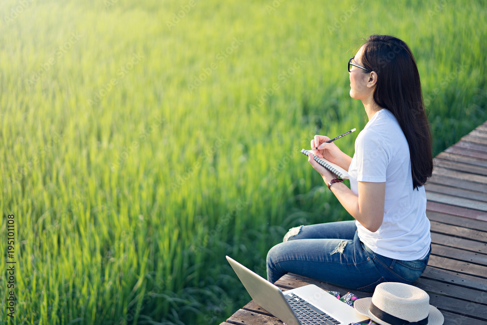 Woman relaxing and working on the bridge in the rice field in the morning. Woman relaxing and working on the bridge in the rice field in the morning.