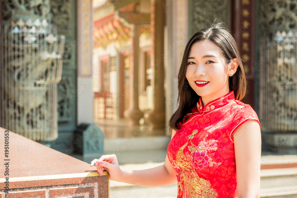 Asian woman in traditional red cheongsam qipao dress at Chinese temple Asian woman in traditional red cheongsam qipao dress at Chinese temple