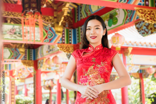 Asian woman in traditional red cheongsam qipao dress at Chinese temple