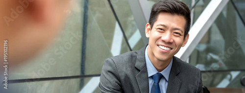 Friendly smiling handsome Asian businessman sitting at office lounge