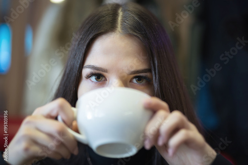 A girl is drinking coffee in a cafe. Small depth of field