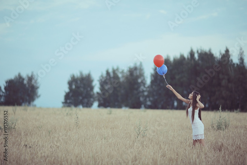 Dream, happiness - young girl in a field with flying balloons