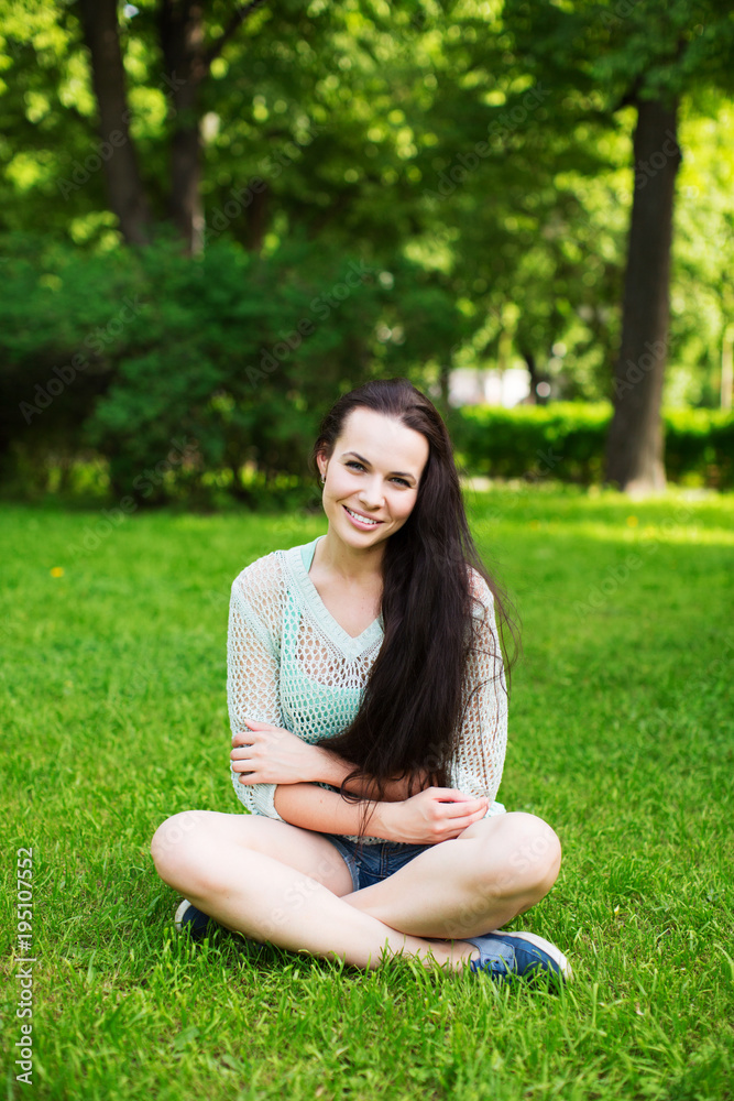Smiling beautiful young woman sitting on grass. Smiling beautiful young woman sitting on grass.