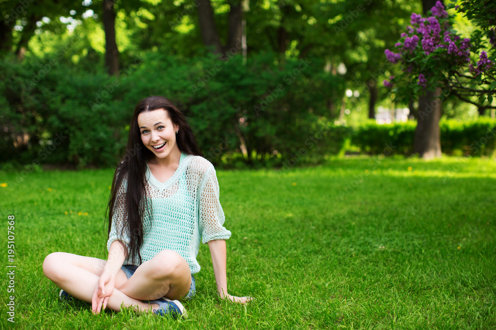 Smiling beautiful young woman  sitting on grass.