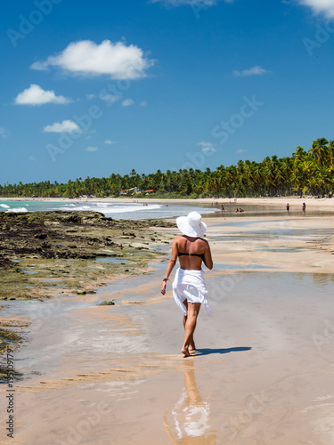 attractive woman walking along beach with view on a summer day
