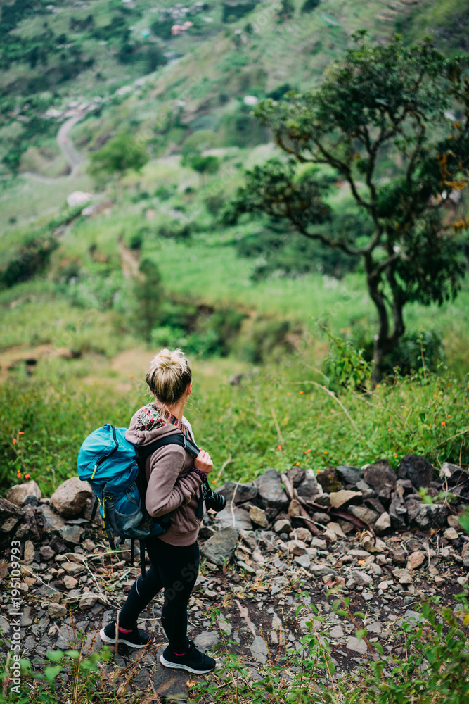 Female hiker with backpack walking down cobbled path to the lush green Paul valley. Santo Antao Cape Verde. Cabo Verde