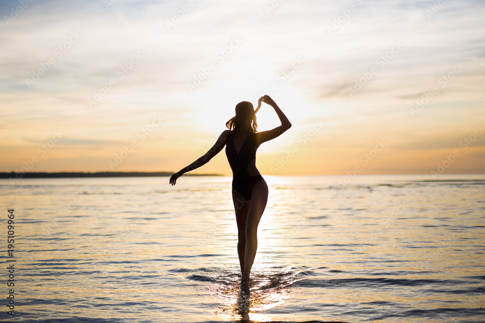 silhouette of slim sexy woman in bikini walking on the beach