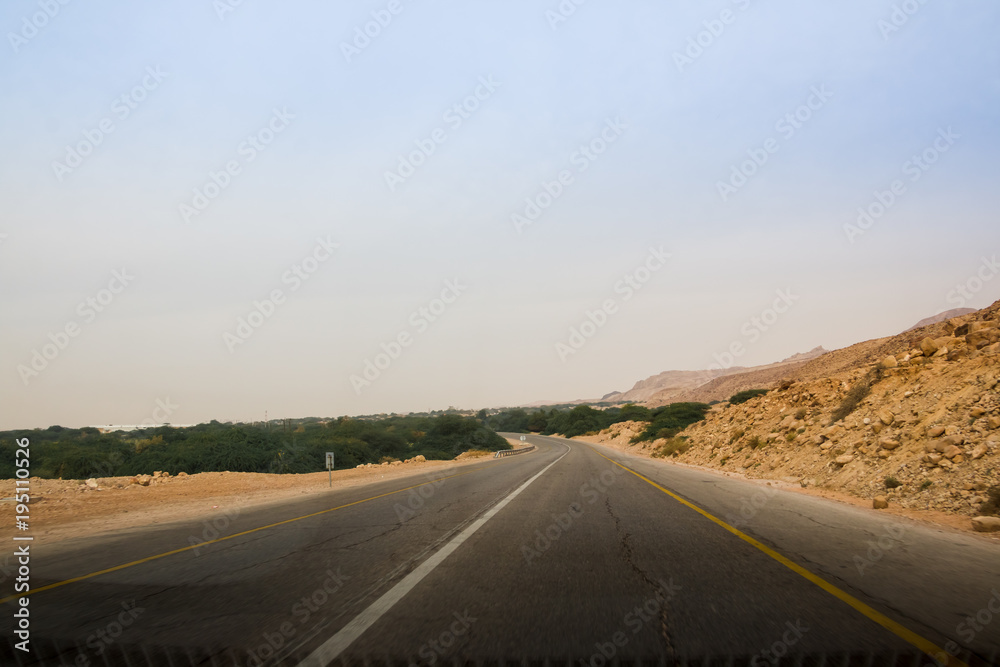 Desert highway and mountains through car window not far from Dead sea