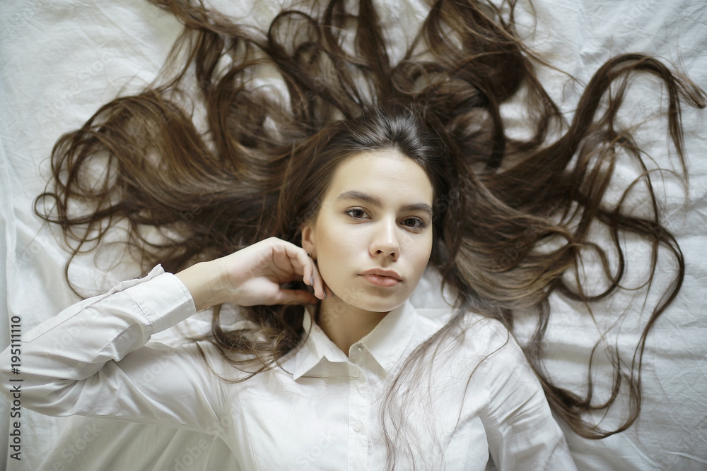 Brunette beautiful young adult with long hair lying on the bed Brunette beautiful young adult with long hair lying on the bed