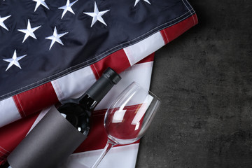 Glass and bottle of wine with American flag on grey background