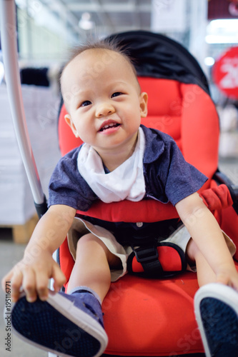 Happy and cute 18 months old / 1 year old Asian Baby toddler boy sitting on stroller shopping in the department store, Kid experience concept