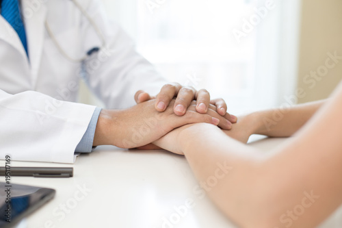 Doctor working at hospital. Doctor try to treat woman for any problem. He holding her hand.