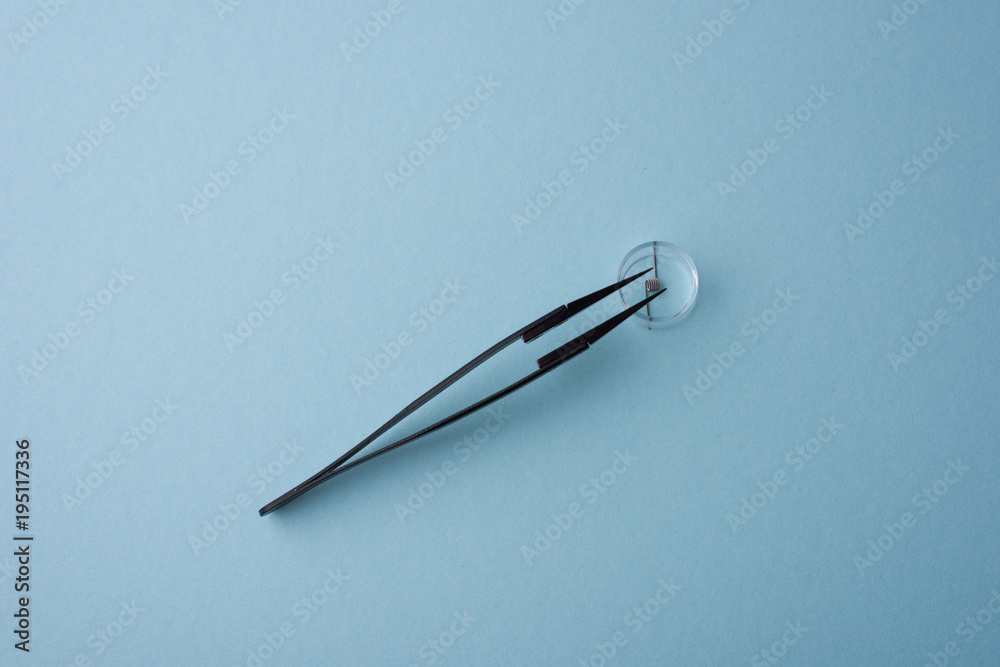 Coil and tweezer for vaping, background blue Coil and tweezer for vaping, background blue