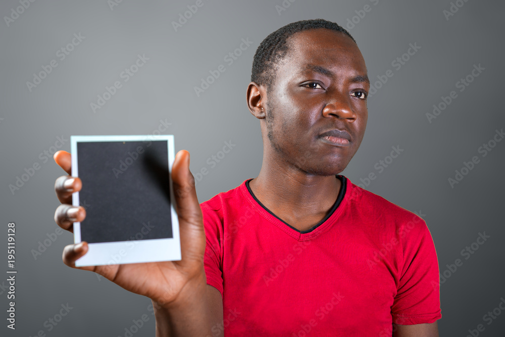 Closeup portrait of young african man holding empty black picture frame with copy space Closeup portrait of young african man holding empty black picture frame with copy space