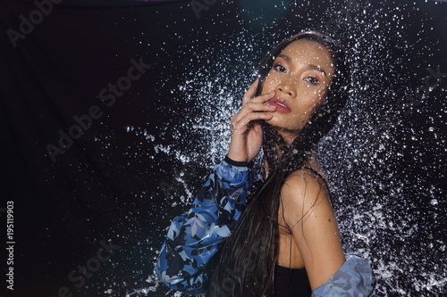 Active Woman rain coat with Water Splash over studio lighting black backgrounds
