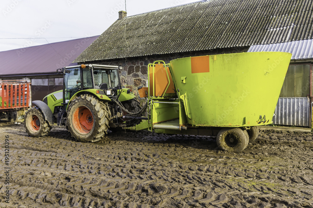Obraz premium Tractor with a trailer on an agricultural farm. Distributor of mixed fodders for cows. Late fall. Podlasie, Poland.