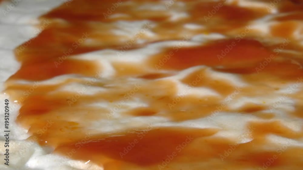 Knife puts ketchup on the dough. Close up. Knife puts ketchup on the dough. Close up.