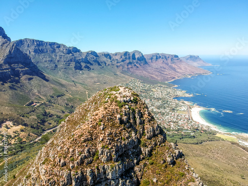 Stunning wide angle aerial drone view of the summit of Lion's Head mountain and the suburb of Camps Bay with the Twelve Apostles mountain range in Cape Town, South Africa. Popular tourist destination.