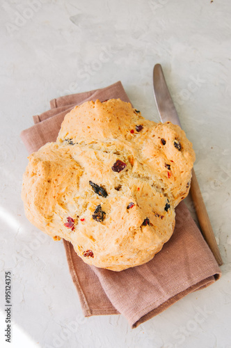 Homemadel Irish soda bread with cranberries and nuts on a napkin on a white stone background. photo