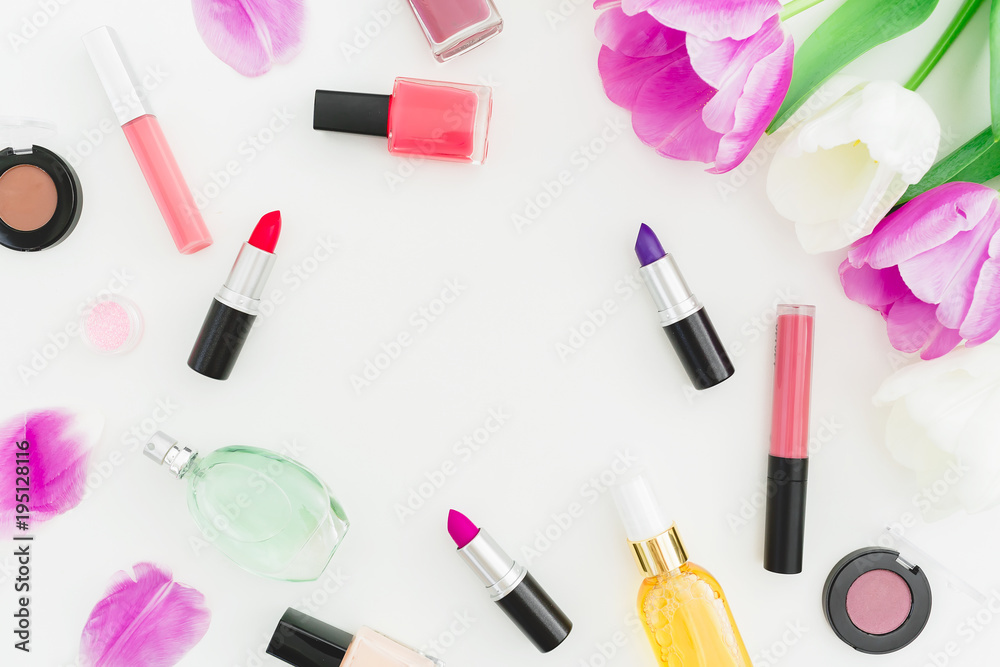 Frame made of tulips flowers and cosmetics, lipstick, nail polish on white background. Top view. Flat lay feminine desk. Frame made of tulips flowers and cosmetics, lipstick, nail polish on white background. Top view. Flat lay feminine desk.