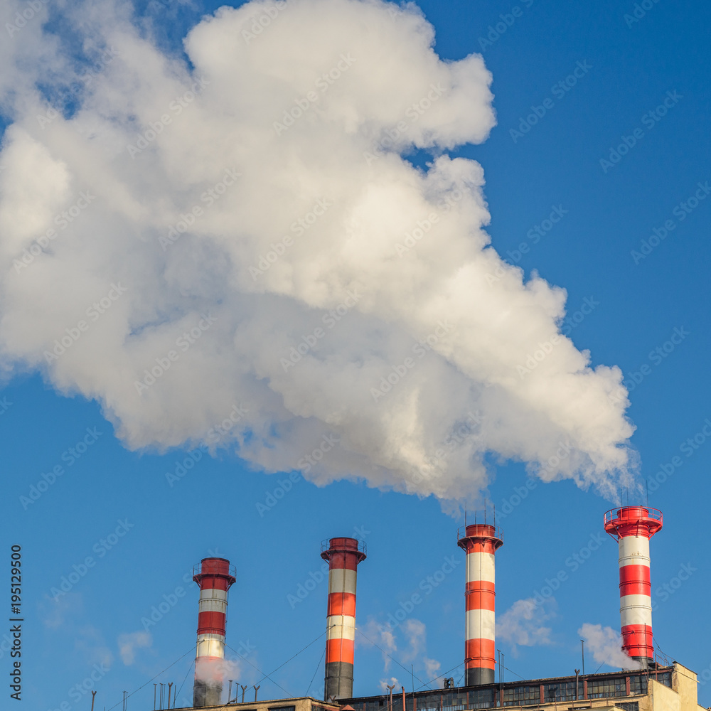 Plant pipes with smoke against clear blue sky.