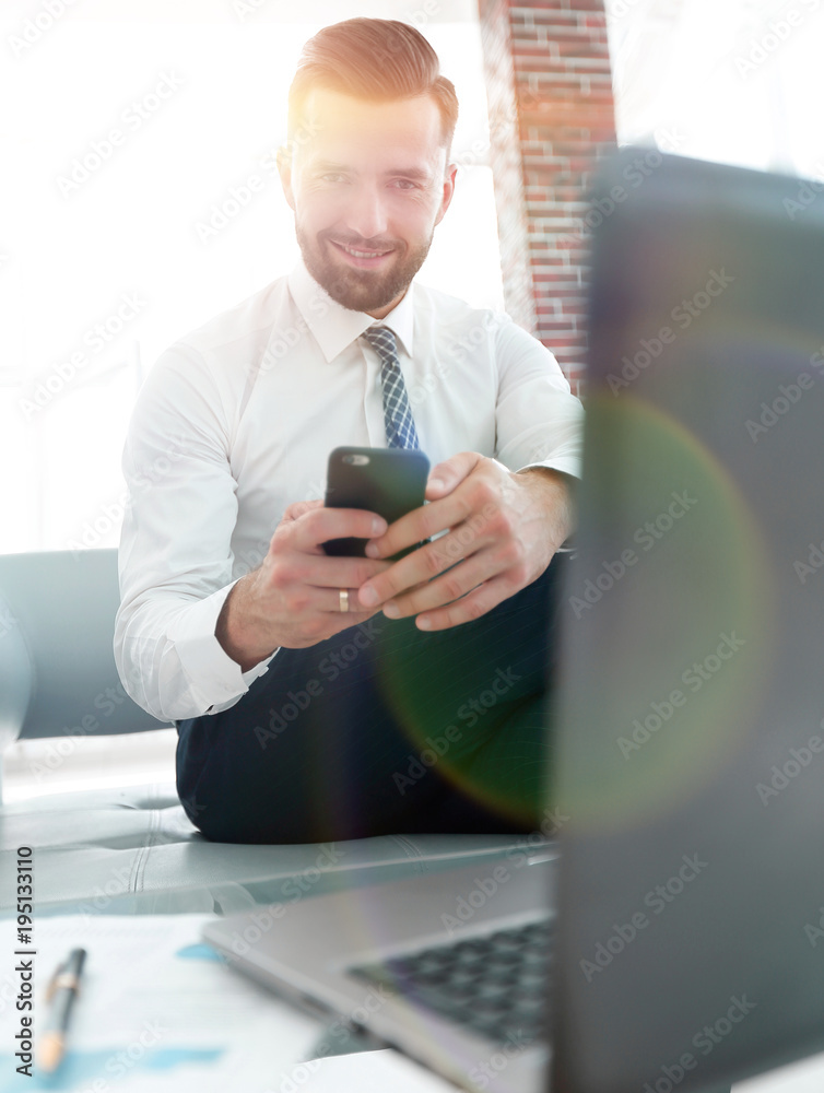 Businessman looking at screen smartphone sitting in front of an Businessman looking at screen smartphone sitting in front of an