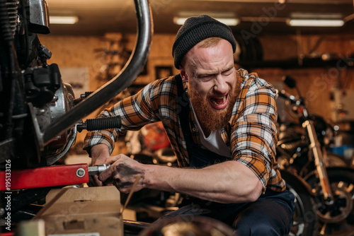 repair station worker trying to fix bike at garage and shouting to colleague