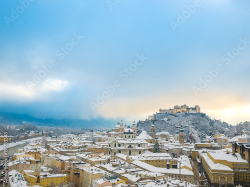 Beautiful scenic winter landscape in historic city of Salzburg with snowy rooftops, cathedrals and famous fortress Hohensalzburg blue sky space