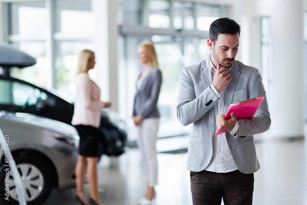 Handsome salesman at car dealership selling vehichles Handsome salesman at car dealership selling vehichles