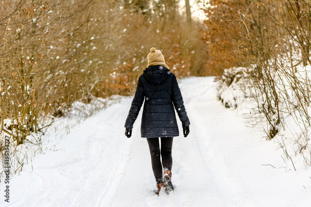 Woman in winter, walking on snow path in the forest Woman in winter, walking on snow path in the forest