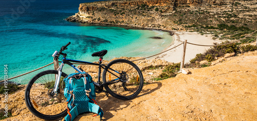 Mountain bike by the sea in Lampedusa, a small island close to Africa, part of the Pelagie islands, Sicily. The Rabbit beach in the background 