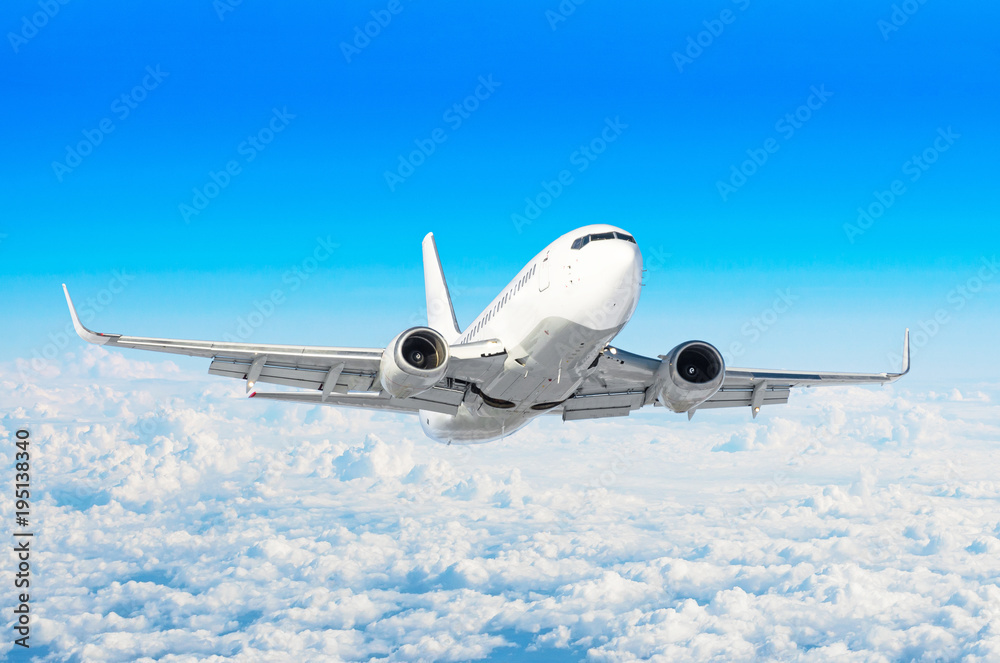 Obraz premium White airplane flies climbs height, flight level high in the sky above the clouds blue sky.