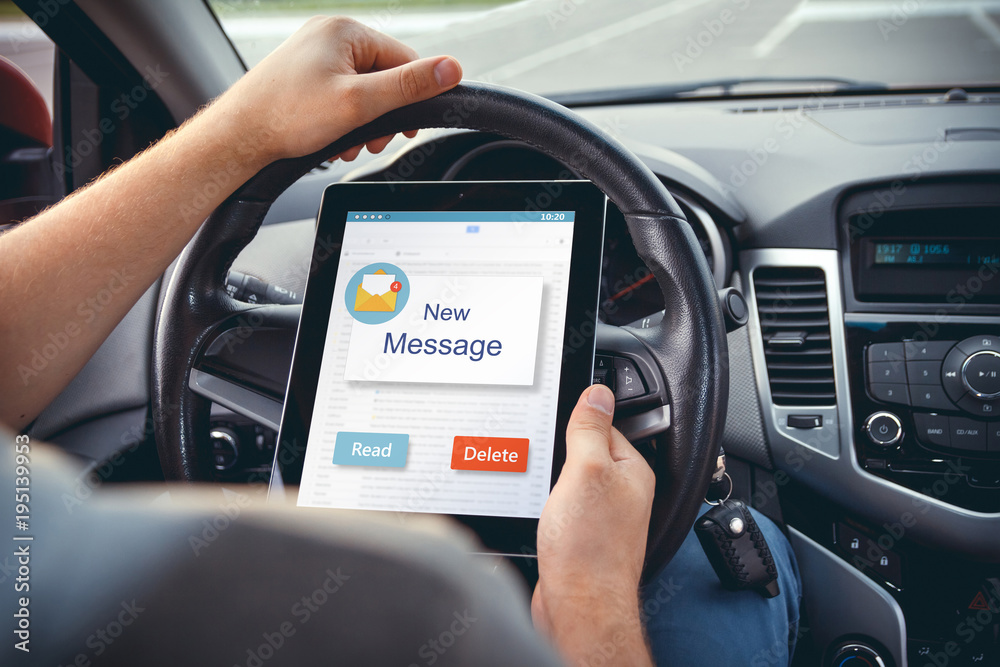 A young man with a tablet in his hand at the wheel of the car. A young man with a tablet in his hand at the wheel of the car.