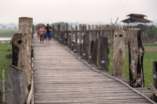 Few people at the U Bein Bridge at Amarapura near Mandalay in Myanmar (Burma) at dusk. It's the oldest and longest teakwood bridge in the world. Focus on the foreground.