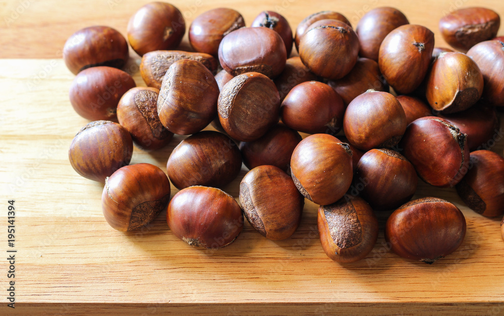 Fresh chestnuts on dark black rustic background. Pile of fresh chestnuts ready to roast shot over black antique background. Top view. Fresh chestnuts on dark black rustic background. Pile of fresh chestnuts ready to roast shot over black antique background. Top view.