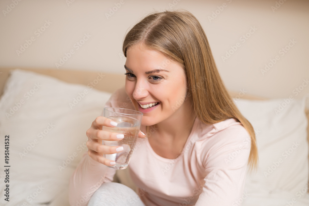 Beautiful woman drinking water and sitting on bed. Beautiful woman drinking water and sitting on bed.