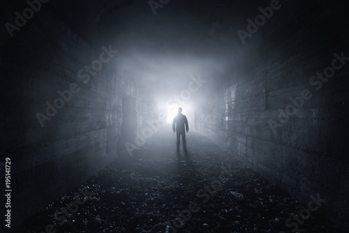 man in a dark concrete tunnel look out the exit - loneliness concept