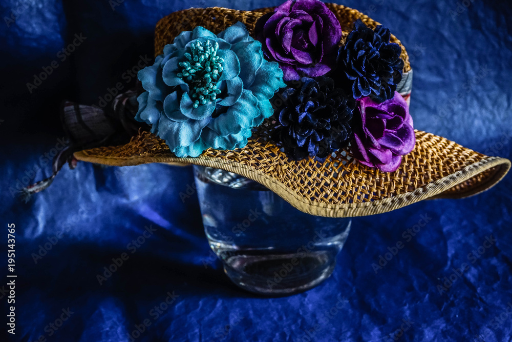 straw hat with artificial flowers in vintage style worn on glass vase