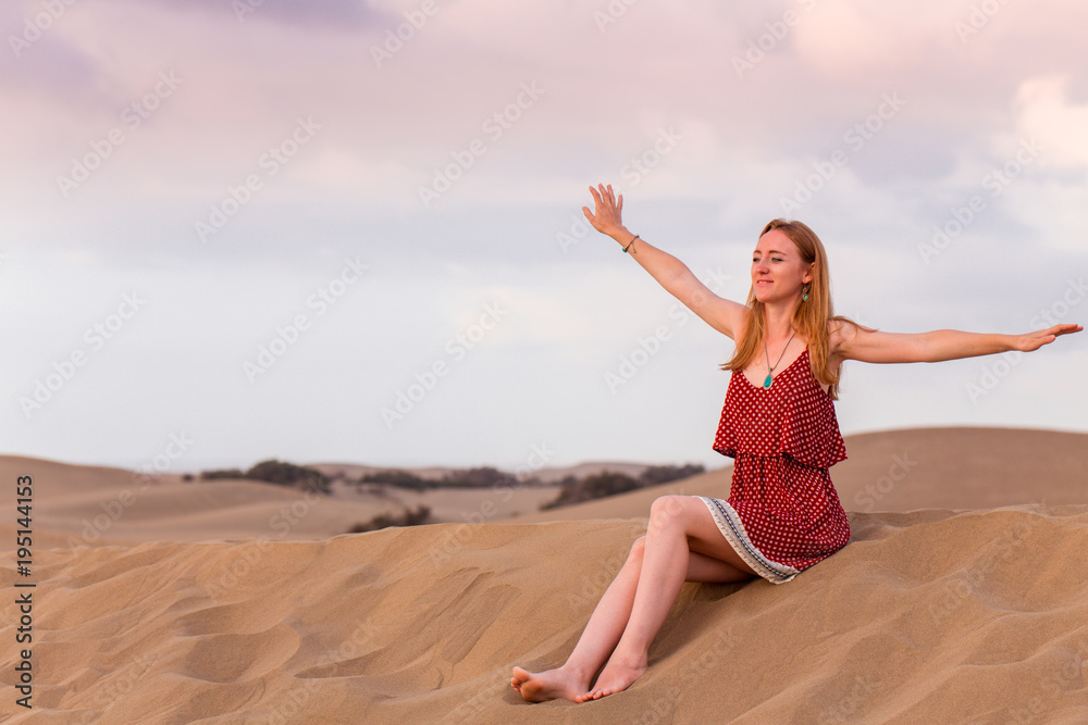 Glückliche Frau sitz auf dem Sand in Maspalomas
