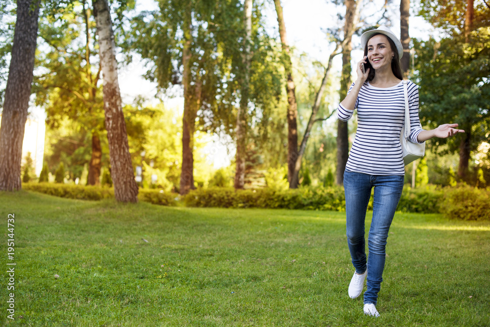 Beautiful young confident woman in casual clothes and a hat on a background of city park. Beautiful young confident woman in casual clothes and a hat on a background of city park.